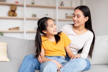 Smiling happy pretty korean millennial woman looking at teen daughter, have fun, enjoying time together