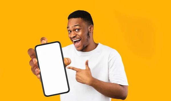 Feliz hombre negro guapo sosteniendo teléfono inteligente con pantalla vacía — Foto de Stock