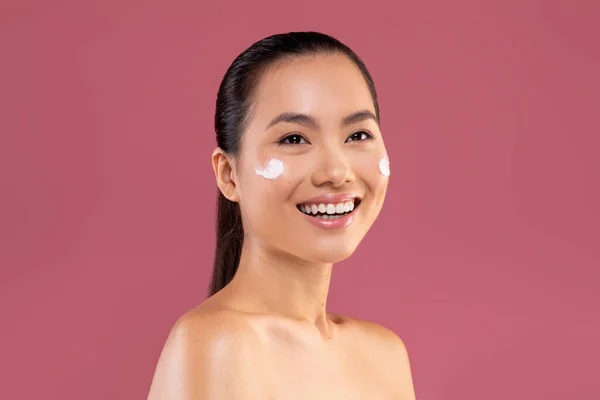 Beautiful asian woman with moisturizer cream on her cheeks — Stock Fotó