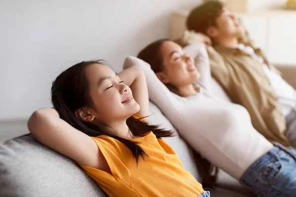 Satisfait adolescent asiatique fille, millénariste maman et papa se détendre sur canapé en silence dans la chambre minimaliste intérieur à temps libre — Photo