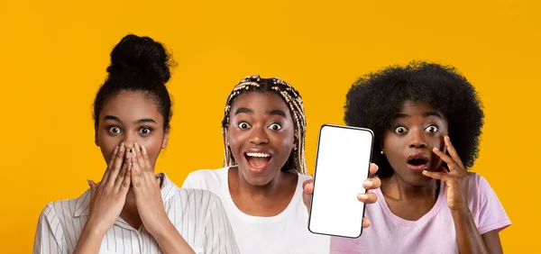 Κατάπληκτες μαύρες γυναίκες που δείχνουν smartphone με άδεια οθόνη, mockup — Φωτογραφία Αρχείου
