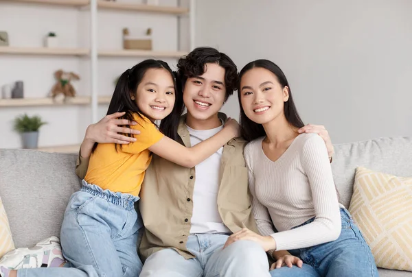 Glad smiling teen chinese girl, millennial family hugging on sofa and enjoy free time in minimalist living room — Fotografia de Stock