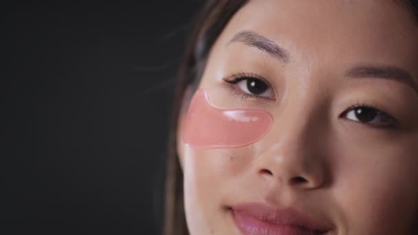 Procedimentos anti-edema. Close up retrato de senhora coreana irreconhecível colocando manchas de hidrogel sob seus olhos — Vídeo de Stock