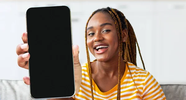 モバイルオファー。大きなブランクスクリーンでスマートフォンを示す陽気な黒人女性 — ストック写真
