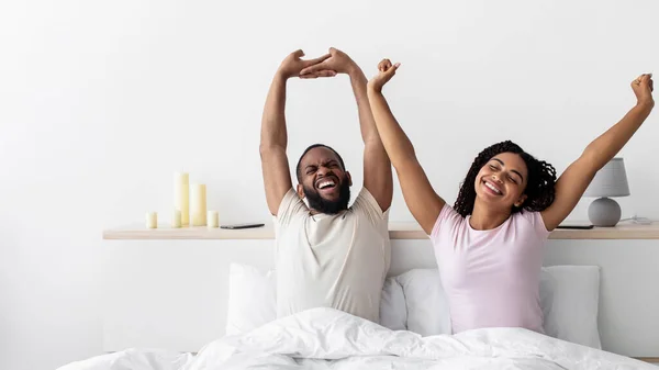 Glad happy young african american lady and guy woke up stretching body and enjoy morning — стокове фото
