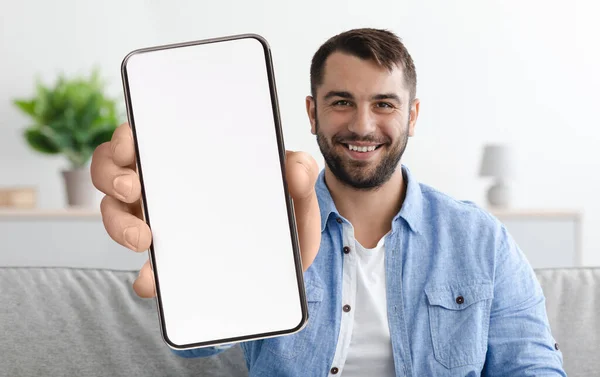 Мобільна пропозиція. Щасливий молодий чоловік демонструє порожній смартфон з великим білим екраном — стокове фото