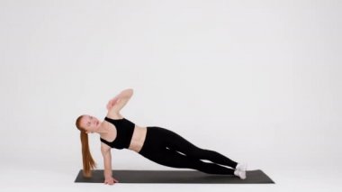Athletic Young Woman Doing Side Plank Rotations Exercise While Training In Studio