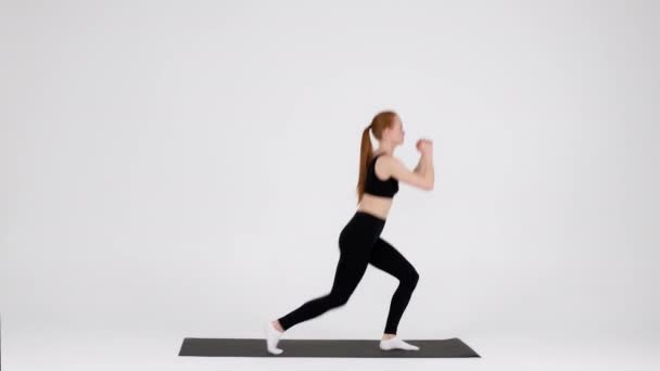 Atlético jovem do sexo feminino fazendo salto lunges exercício durante o treinamento em estúdio — Vídeo de Stock