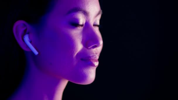 Beautiful Asian Lady Wearing Wireless Airpods Listening Music Illuminated By Neon Light — Stock Video