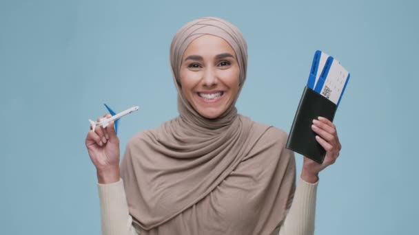 Young happy middle eastern woman wearing headscarf carrying toy airplane and flight tickets, enjoying future journey — Vídeo de Stock