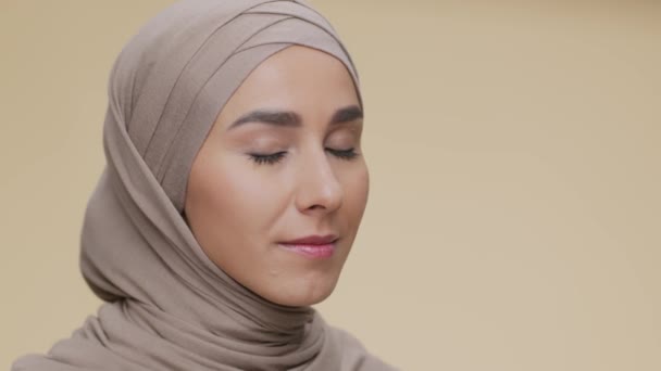 Muslimská krása. Krásná šťastná středovýchodní dáma v šátku s úsměvem na kameru přes béžové pozadí, prázdné místo — Stock video
