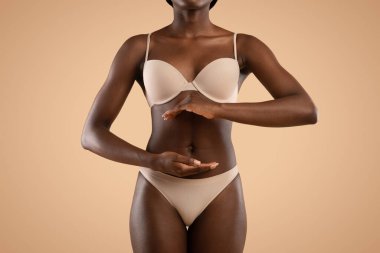Cropped of black lady in lingerie holding hands by belly