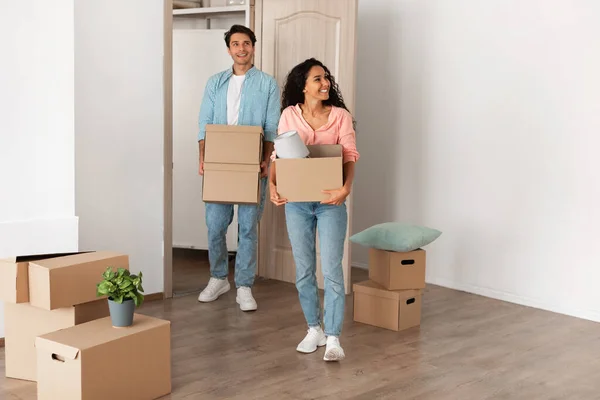 Casal feliz segurando caixas de papelão, andando em casa nova — Fotografia de Stock