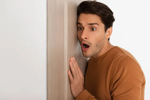 Shocked young guy listening through the door