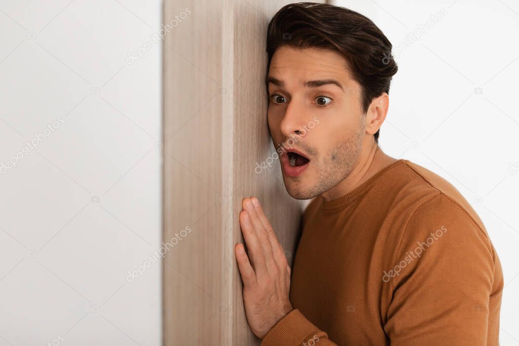 Shocked young guy listening through the door