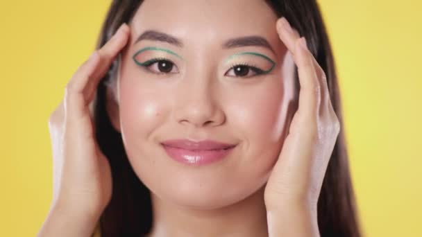 Modeporträtt. ung vacker asiatisk kvinna med kreativ konst makeup poserar till kameran över gul studio bakgrund — Stockvideo