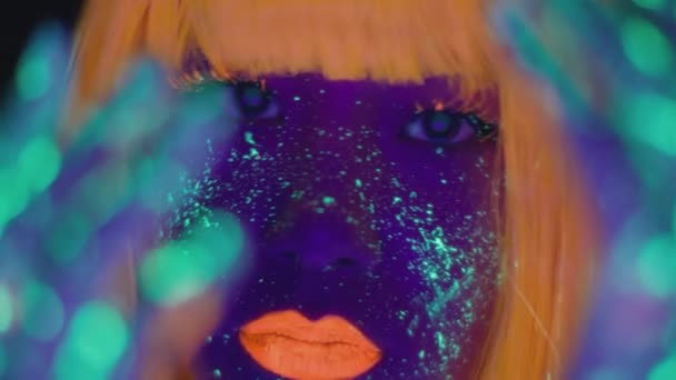 Fashion model in neon lights. Close up portrait of young asian lady with bright fluorescent makeup posing to camera — Stock Video