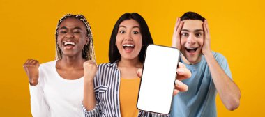 Cool multiethnic friends enjoying online offers, showing cellphone, mockup