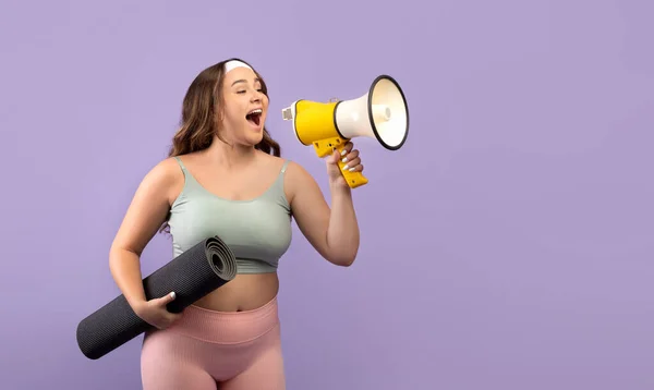 Funny millennial caucasian lady plus size in sports uniform with mat screaming at megaphone at free space — Φωτογραφία Αρχείου