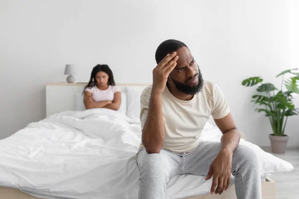 Malheureux jeune homme afro-américain triste ignore femelle dans un lit confortable à l'intérieur de la chambre, espace vide — Photo