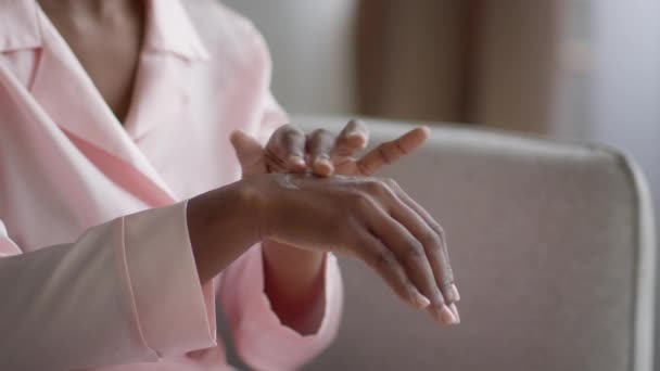 Strzał afrykańskiej kobiety nawilżające ręce stosując krem w pomieszczeniach — Wideo stockowe