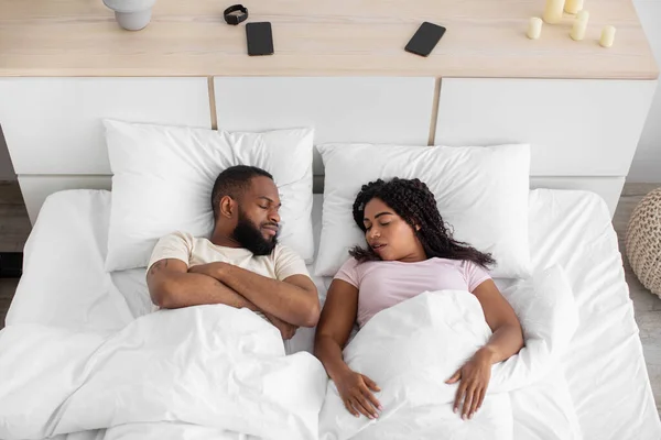 Genç Afrikalı Amerikalı karı koca, yumuşak yastıklı, beyaz battaniyeli rahat bir yatakta yatıyorlar. — Stok fotoğraf