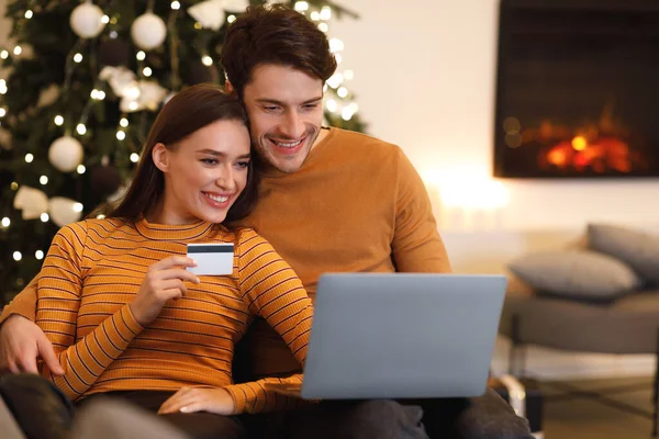 Happy couple using pc and debit credit card at home — ストック写真