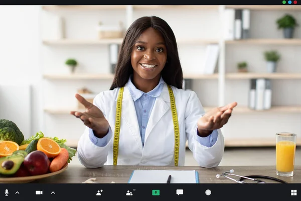 Allegro nutrizionista afro-americano che offre consulenze online sul posto di lavoro in ambulatorio, visualizzazione dello screenshot — Foto Stock