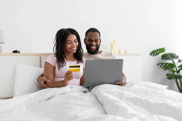 Smiling millennial african american guy with computer and lady with credit card shopping online — Stockfoto
