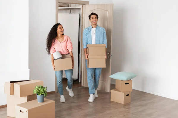 Casal feliz segurando caixas de papelão, andando em casa nova — Fotografia de Stock