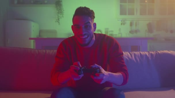 Tv pov portrait of emotional middle eastern guy playing video games with joystick, sitting on sofa at home in evening — Video Stock