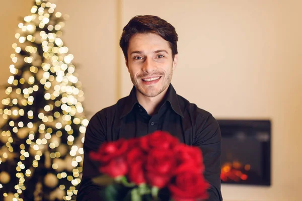Smiling man holding roses, giving to camera — Stok fotoğraf