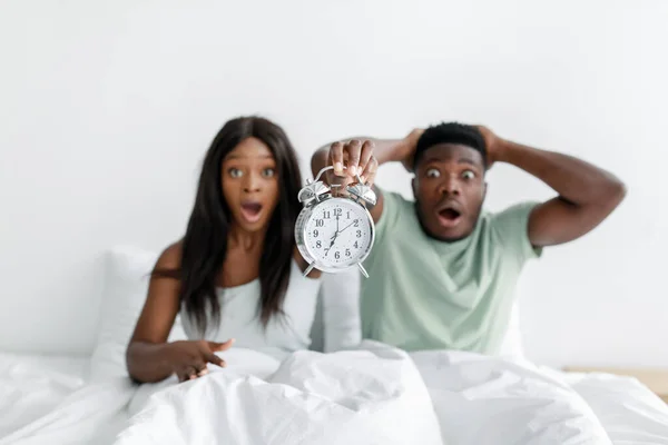 Shocked funny young african american woman and husband with open mouths overslept, wake up after night sleep — Stock Photo, Image