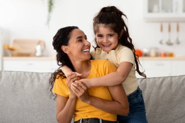 Happy Young Arab Mom And Her Cute Preteen Daughter Hugging At Home