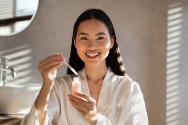 Smiling attractive korean woman showing newest beauty product