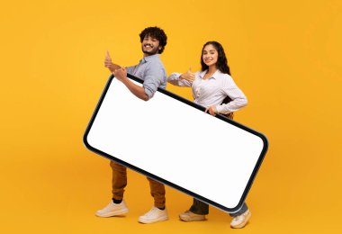 Mutlu Hintli çift tasarım, reklam uygulaması ya da web sitesi için büyük bir akıllı telefon tutuyor.
