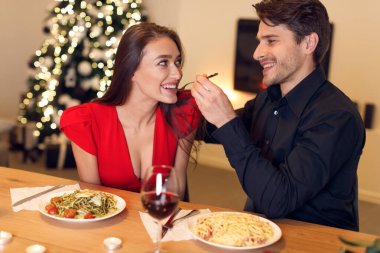 Handsome guy feeding his woman with pasta