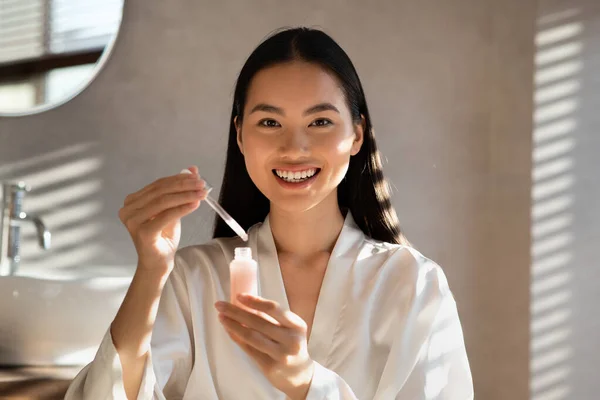 Mujer coreana atractiva sonriente mostrando el producto de belleza más nuevo — Foto de Stock