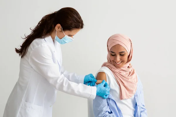 Doctor Applying Sticking Plaster On Muslim Womans Shoulder After Vaccine Injection Shot — Stock Fotó