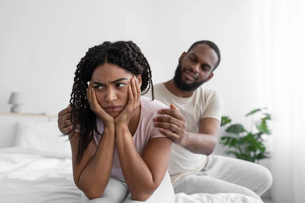 Millennial african american husband calm his wife, sit on comfort bed in bedroom interior — Fotografia de Stock