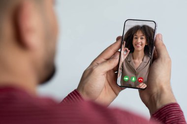 Unrecognizable guy using smartphone, having online party with girlfriend