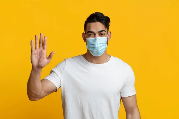 Arabic man in face mask waving hand on yellow — Stok fotoğraf