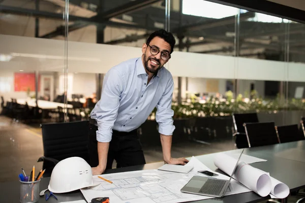 Souriant millénaire attrayant ingénieur musulman constructeur de lunettes de travail sur bureau avec des dessins de projet — Photo