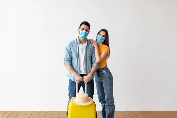 New travel rules. Loving couple in face masks, standing with luggage ready for vacation trip during coronavirus pandemic — 스톡 사진