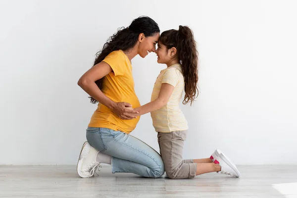 Excited little daughter touching moms pregnant belly, bonding with mother at home — Stock fotografie