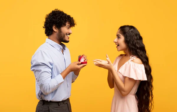 Homme indien passionné demandant en mariage à sa bien-aimée dame, lui donnant sa bague de fiançailles le jour de la Saint-Valentin, fond jaune — Photo