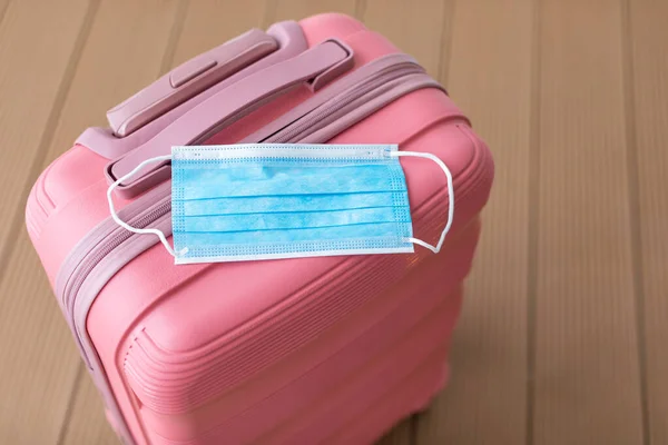 Travel concept under the conditions and restrictions due to Coronavirus 2019-nCov. Pink suitcase with medical face mask — ストック写真