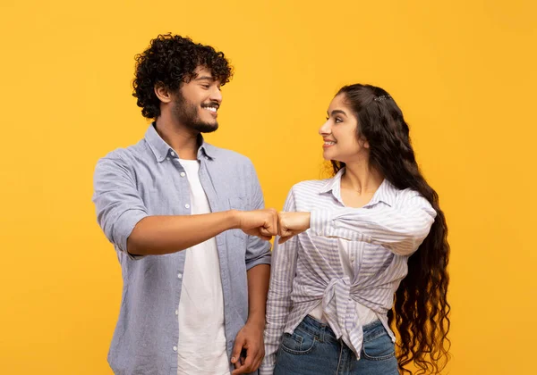 Partnership and collaboration work as team. Young indian woman and man making fist bumps, posing on yellow background — Foto de Stock