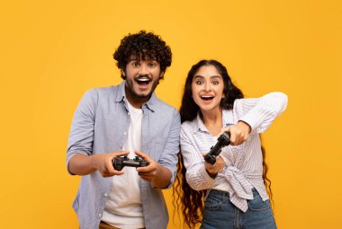Boş zaman eğlence konsepti. Neşeli Hintli çift birlikte video oyunu oynuyor, joystickleri tutuyor ve kullanıyorlar.