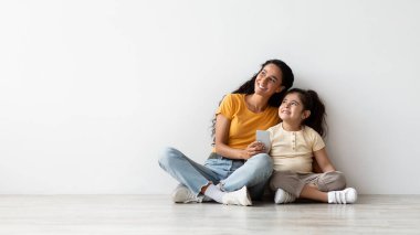 Mobile Offer. Mom And Little Daughter Holding Smartphone And Looking Aside